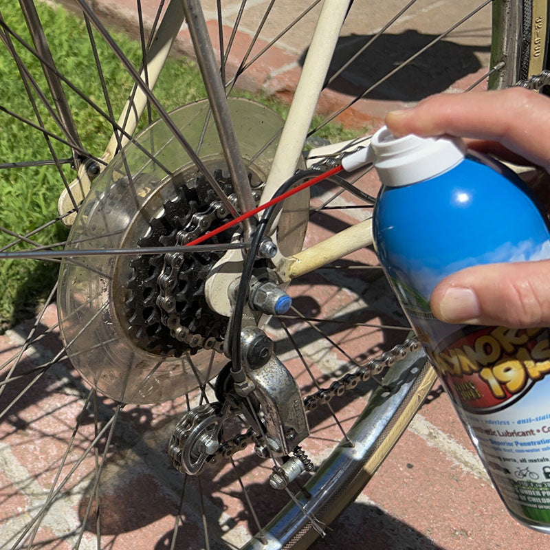 An aerosol can of Jaymor's synthetic lubricant being used on a bike chain.