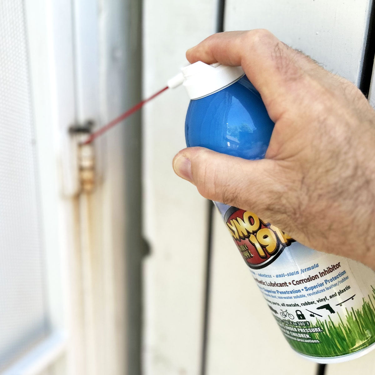 A rusty door hinge being sprayed with Jaymor's synthetic lubricant.
