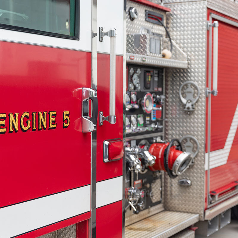 The side of a firetruck shown with hoses, controls, and gauges.