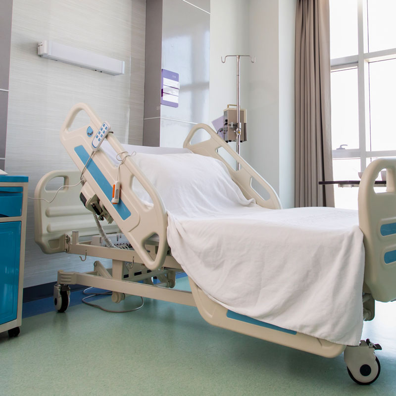 A mechanical patient bed with wheels shown in a care facility.